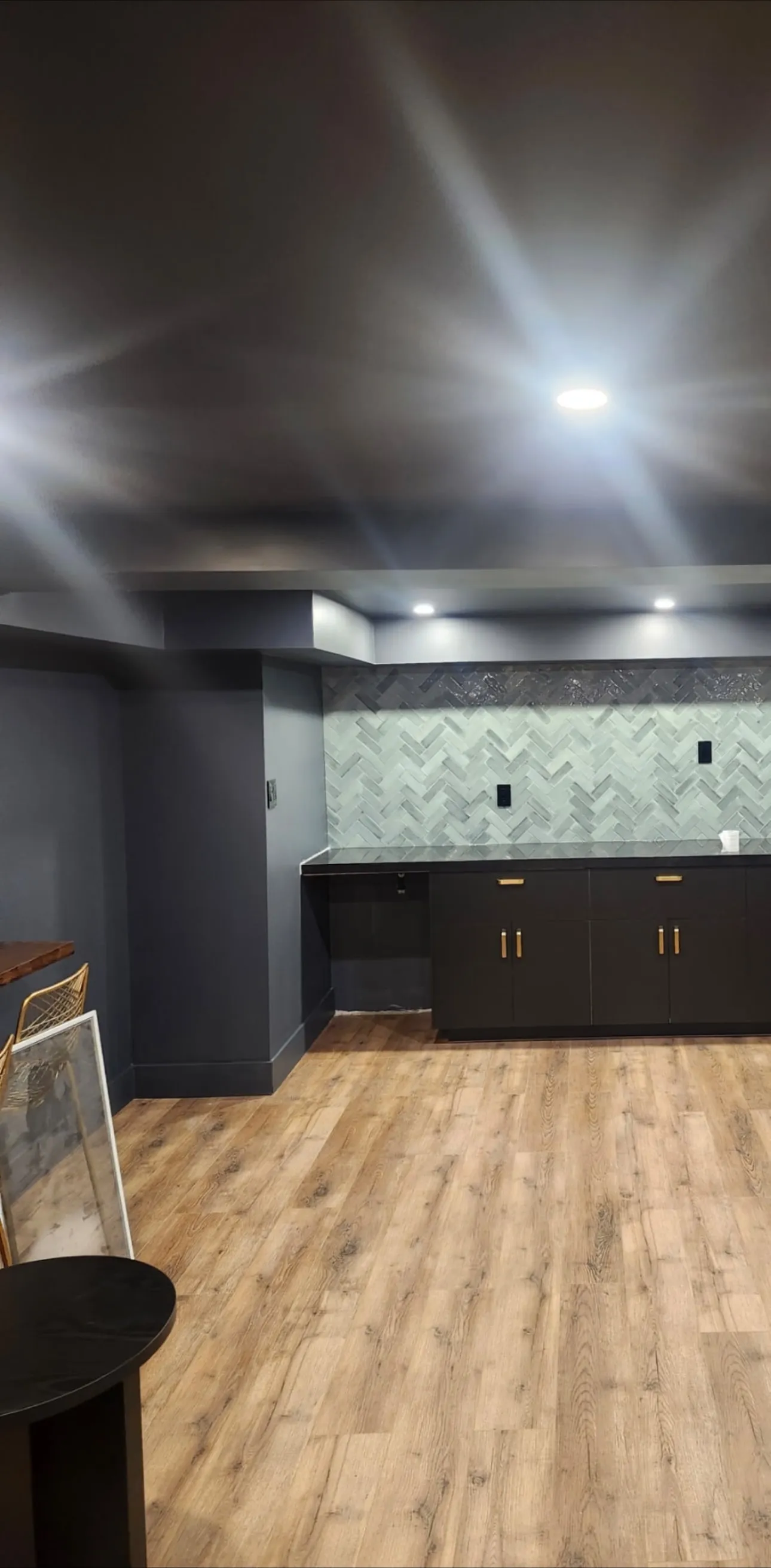 Deep navy walls framing a bar with herringbone tile and black cabinets