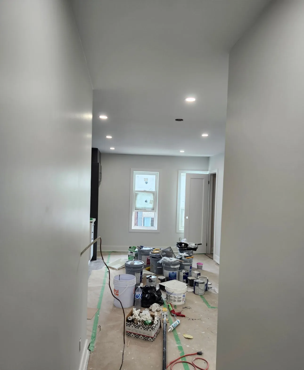 Hallway with floors covered in paper and tape while walls are painted