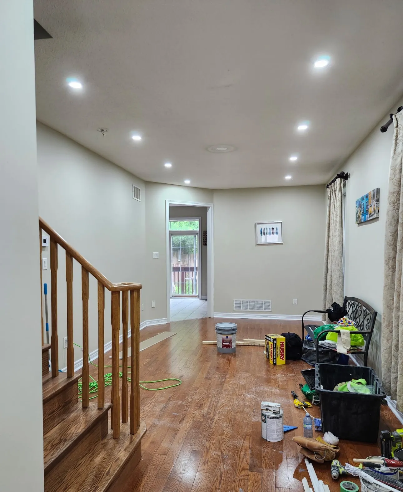 Main-floor living room repainted in warm greige beside an oak staircase