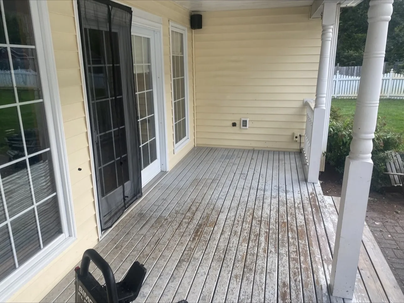 The same porch deck before, with grey peeling paint and bare boards