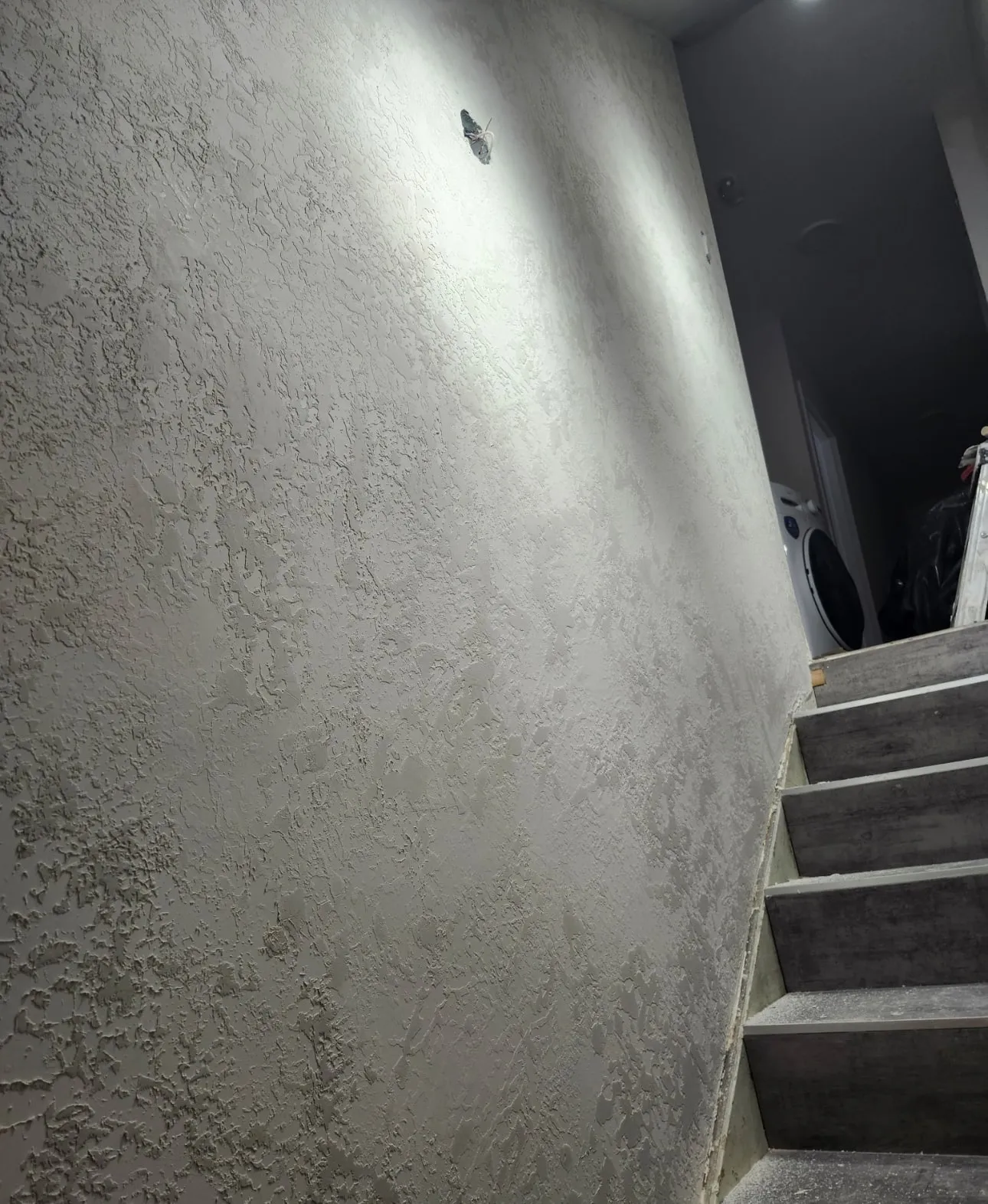 Textured stairwell wall with a hole to be filled and blended before painting