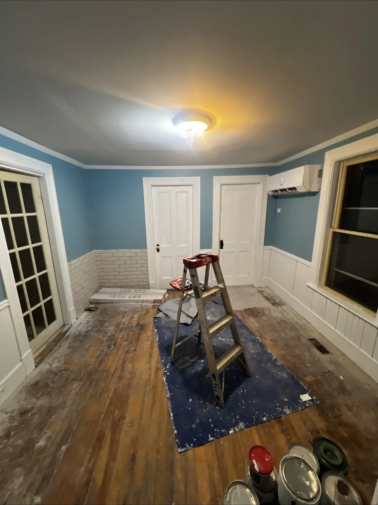 Bedroom finished in blue with white brick-style wainscoting and trim after wall repairs