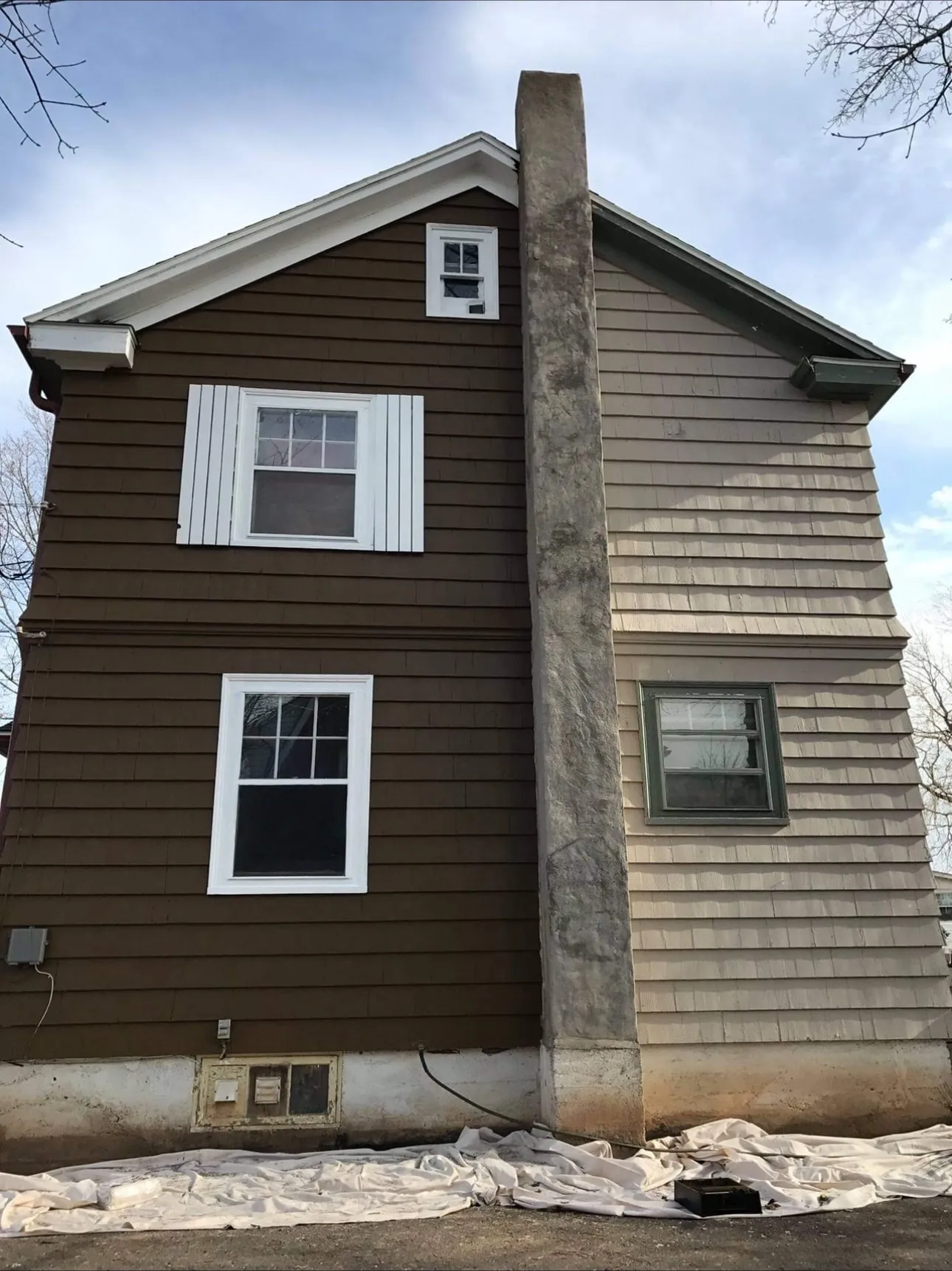 House siding mid-repaint, new brown on the left and the original beige on the right