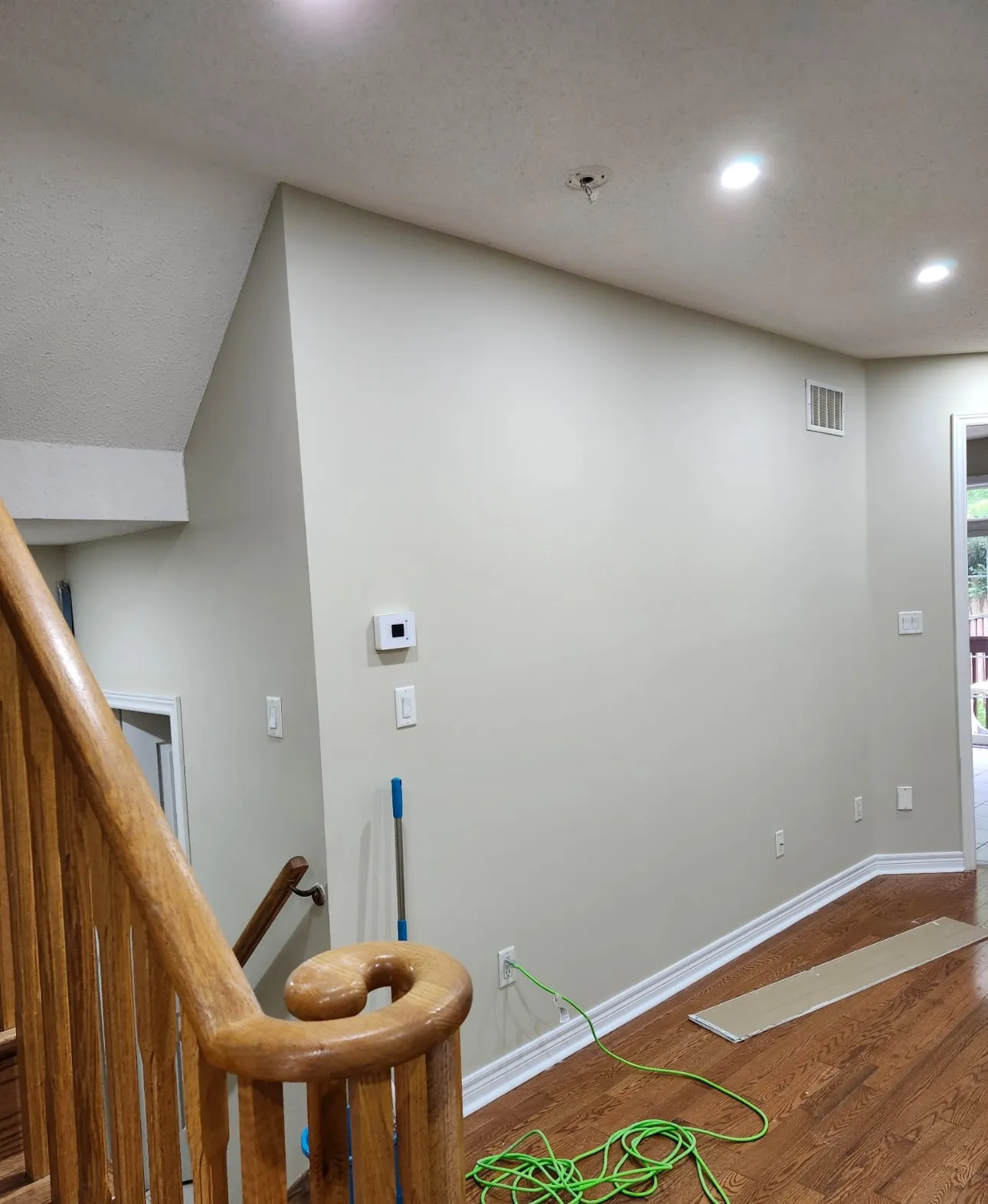 Smooth repainted wall beside an oak staircase with clean lines at the baseboard