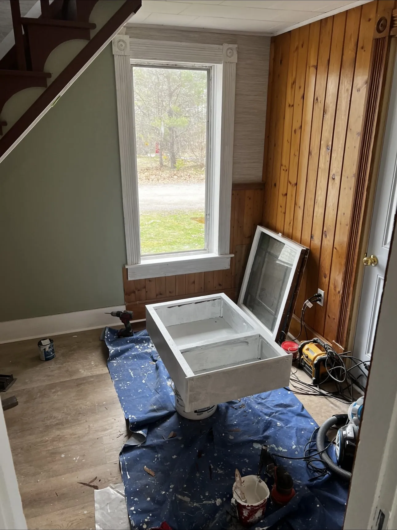 Window casing primed white with a sash being painted on drop cloths